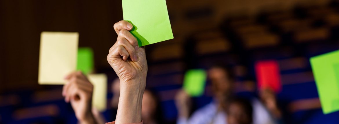 Business executives show their approval by raising hands at conference center